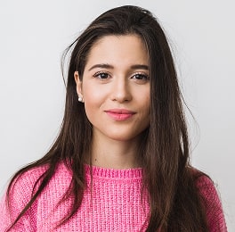 A dark-haired woman in a pink sweater